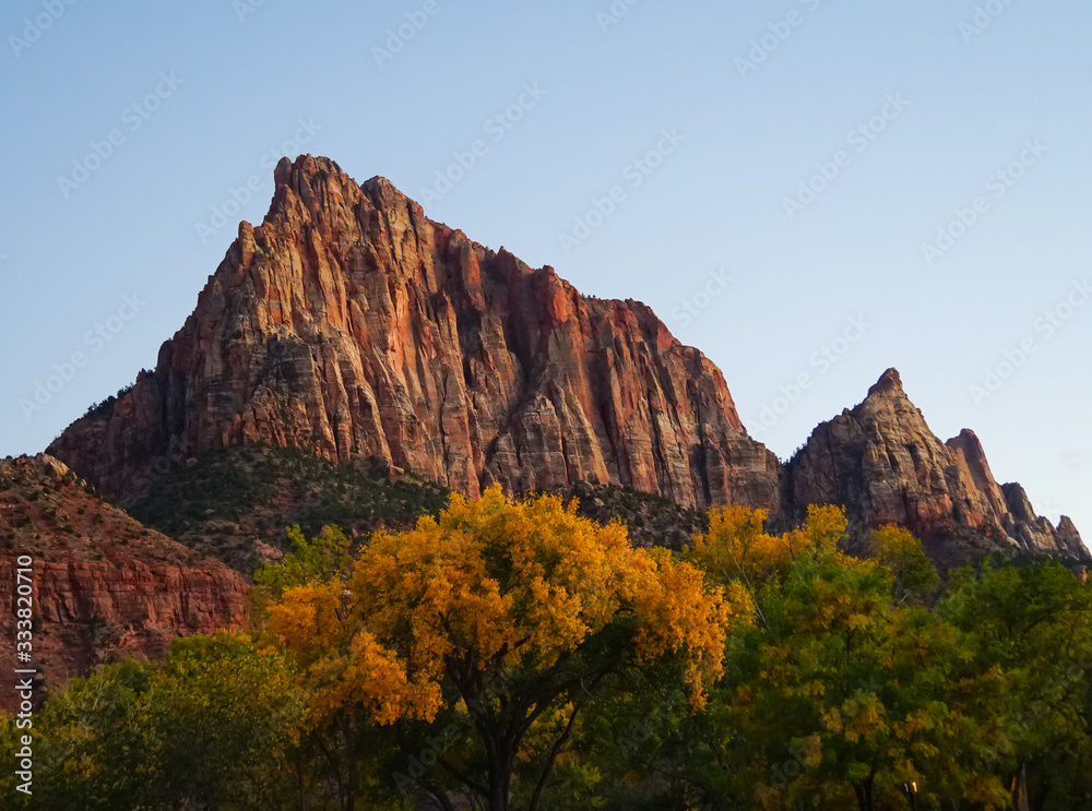 The last rays of the autumn sun illuminate a beautiful red rock mountain in Zion National Park.