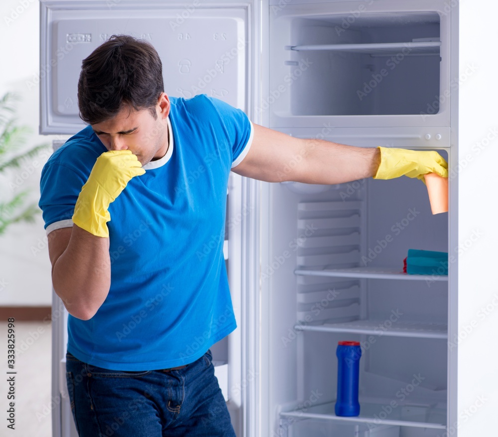 Man cleaning fridge in hygiene concept Man cleaning fridge in hygiene concept