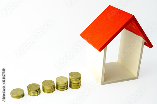 Wooden mini house with coins on the white backgound. Housing loan, housing insurans concept, buying house concept. photo