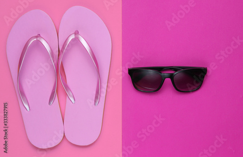Summer still life. Beach accessories. Fashionable beach pink flip flops, sunglasses on colored paper background. Flat lay. Top view