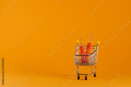 Coronavirus concept. Vaccine. Vaccine in a shopping cart on a yellow background. Covid Virus 2019. Copy space.