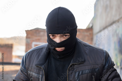 Fotografiet a bandit, a terrorist in a black mask and jacket in a slum and on the territory