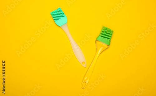 Kitchen spatula and brush on yellow background. Top view