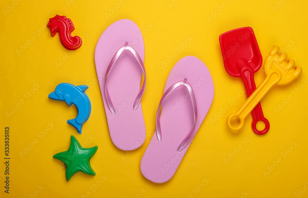 Children's beach toys, flip flops on a yellow background. Beach Vacation Concept. Top view
