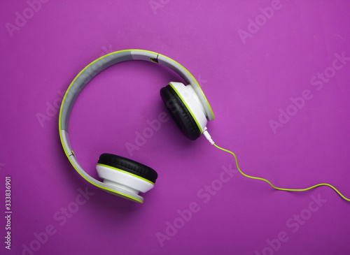 Stylish wired stereo headphones on purple background. Music lover. Gadgets. Top view.