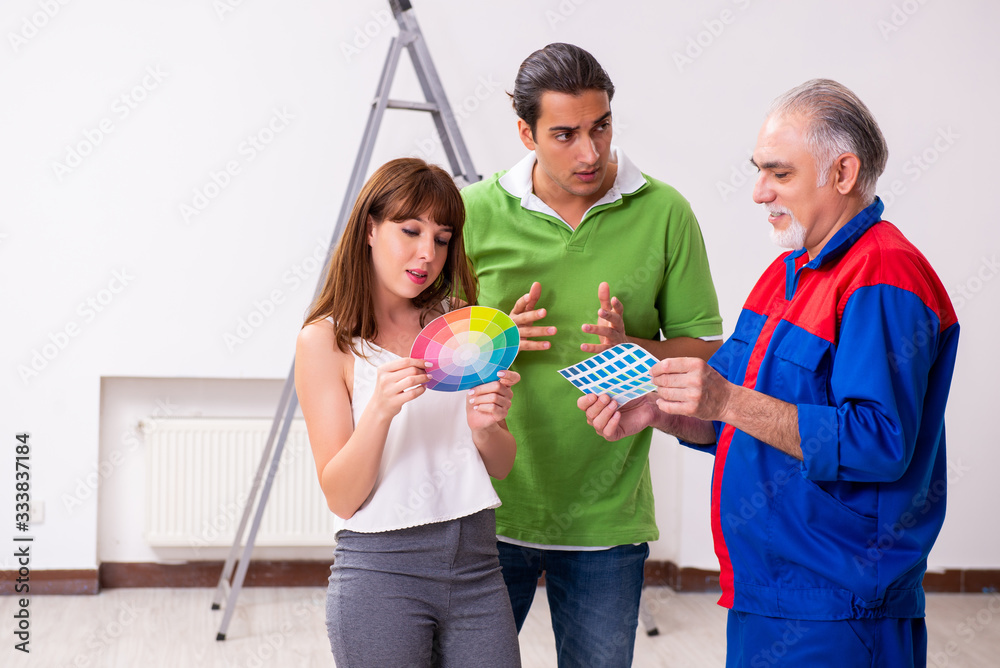 Young couple and old contractor in home renovation concept Young couple and old contractor in home renovation concept