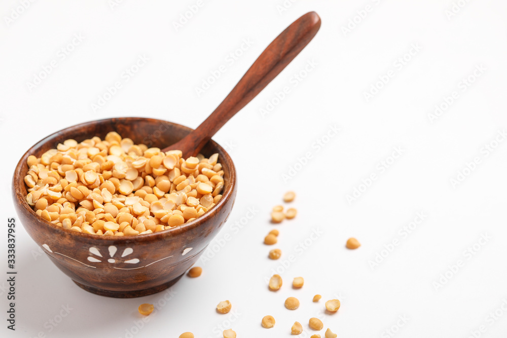 Dried chickpea lentils in wooden bowl and spoon on white background , Split Chickpea Also Know as Chana Dal Dried chickpea lentils in wooden bowl and spoon on white background , Split Chickpea Also Know as Chana Dal