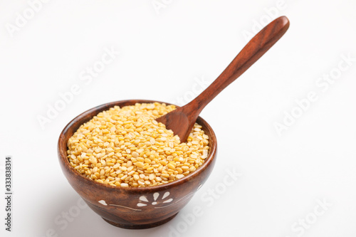 yellow moong mung dal lentil pulse bean in wooden and spoon bowl on white background