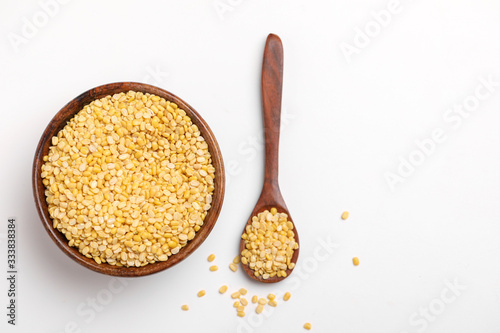 yellow moong mung dal lentil pulse bean in wooden spoon on white background