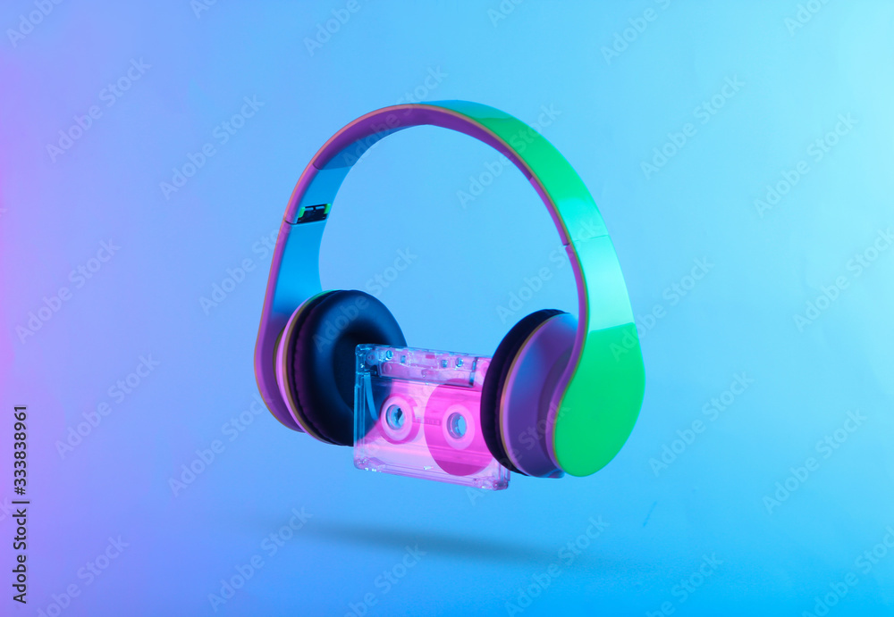 Stereo headphones with audio cassette. Neon vibrant pink-blue light. Gradient glow. Retro wave 80s Stereo headphones with audio cassette. Neon vibrant pink-blue light. Gradient glow. Retro wave 80s