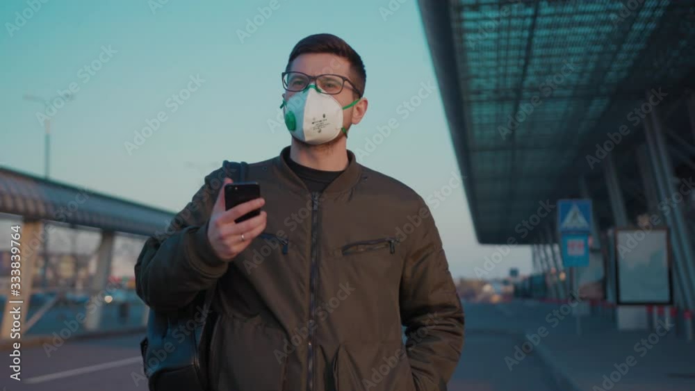 COVID-19 coronavirus infection man with backpack wearing Protective Face Mask use phone coughs hold suitcase near airport pandemic disease virus male tourist epidemic air health illness