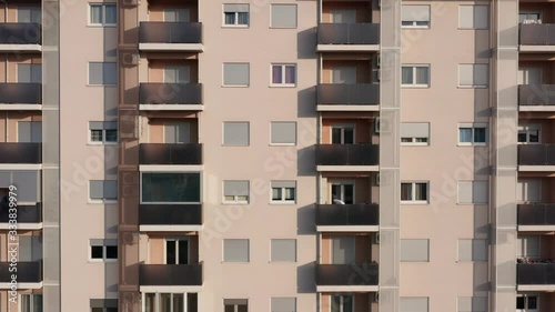 Exterior of a high-rise multi-story apartment building - facade, windows and balconies. Establishing shot aerial footage.