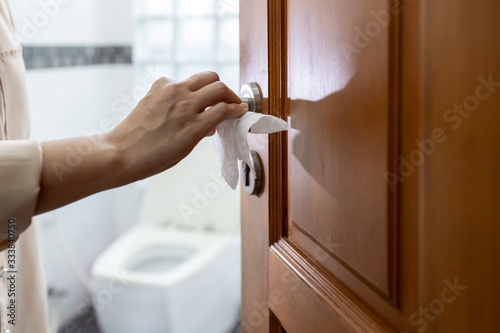 Hand with door handle,girl open the bathroom door,woman using tissue paper to touch the door knob instead of hands to prevent infection of Covid-19,outbreak of Coronavirus,pandemic,contagious diseases photo