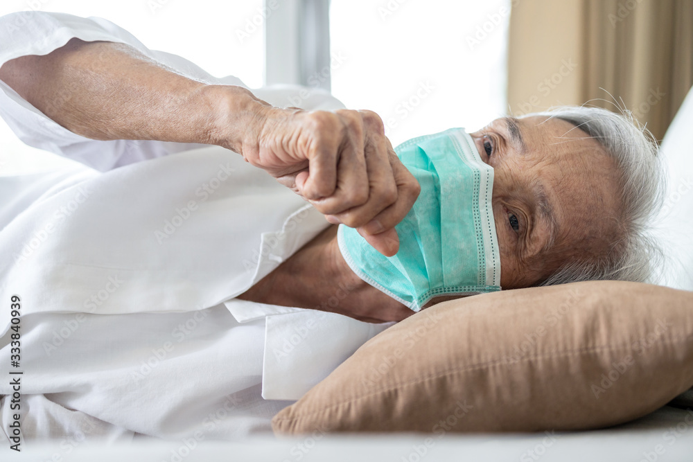 Obraz premium Sick asian senior woman in bed,wear face protection mask,fever and coughing,pneumonia disease,elderly patient has ill,flu and cold,symptoms of Covid-19,pandemic,old people infected with Coronavirus
