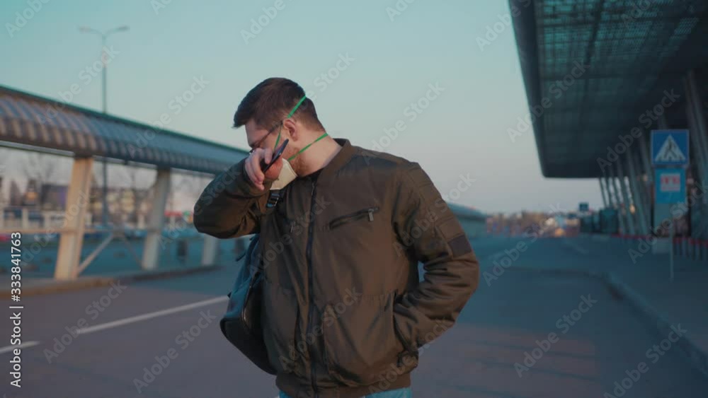 COVID-19 coronavirus infection man with backpack wearing Protective Face Mask use phone coughs hold suitcase near airport pandemic disease virus male tourist epidemic air health illness slow motion