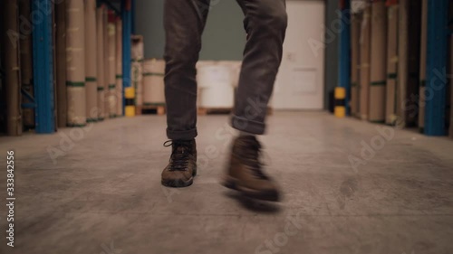Low section of a factory worker dancing in the large distribution warehouse filled with boxes on shelves photo