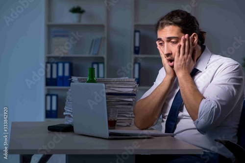 Alcohol addicted businessman working late in the office