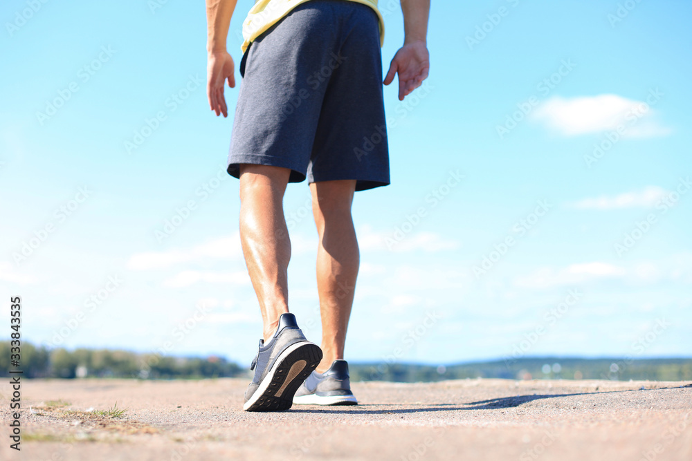 Runner feet running on road closeup on shoe, outdoor at sunset or sunrise Runner feet running on road closeup on shoe, outdoor at sunset or sunrise