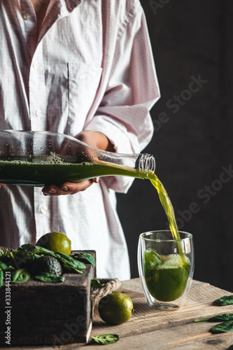 Woman pours spinach smoothie into a glass, detox, wholesome food, vegan, eco. Body cleansing