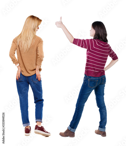 Back view of two woman in sweater showing thumb up.