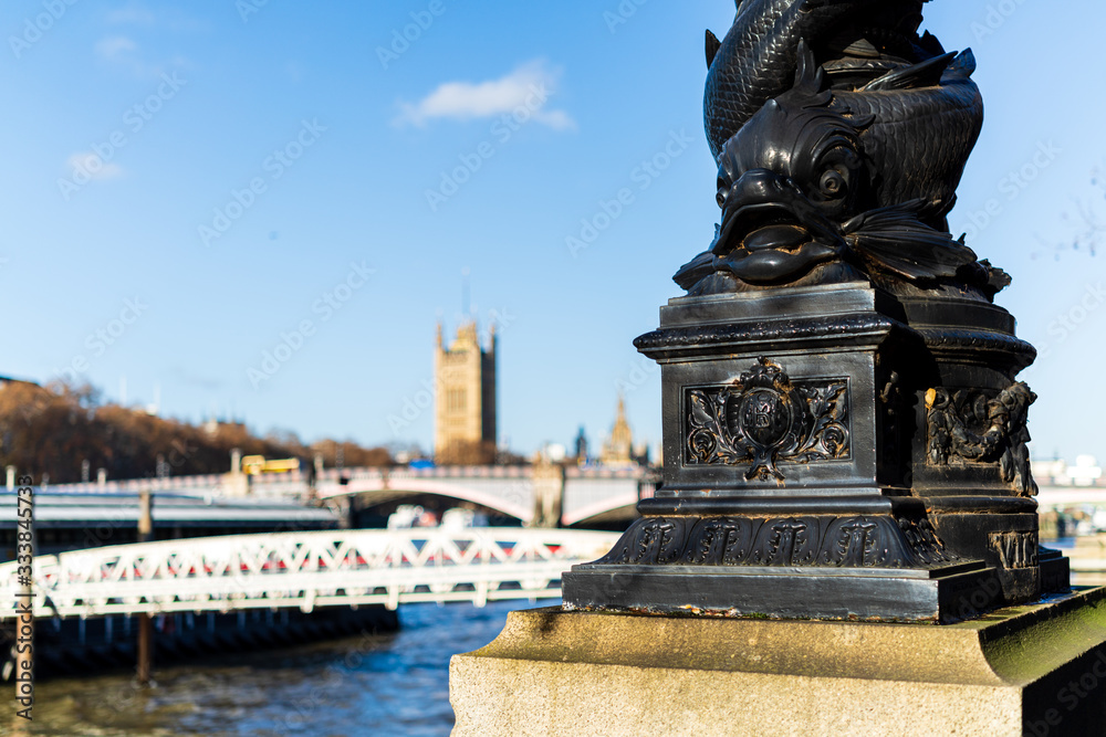 London, England - November 29 2019 : Lamp post base of fish on Thames riverside with houses of parliament blurred in background, in London, England