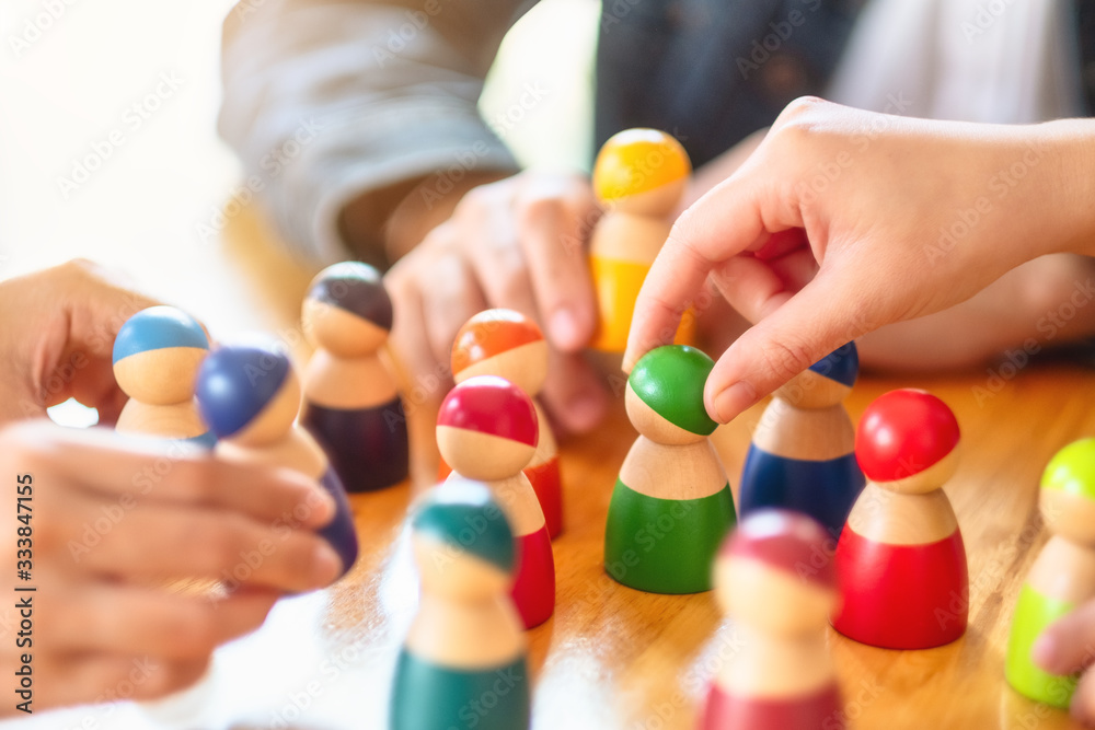 People choosing and picking up wooden figure from a group on the table People choosing and picking up wooden figure from a group on the table