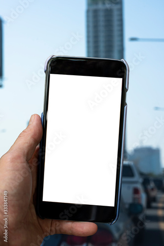 Blank mobile phone holding by a guy seeing a really bad and jam traffic, as usually see in a big city, in a background.