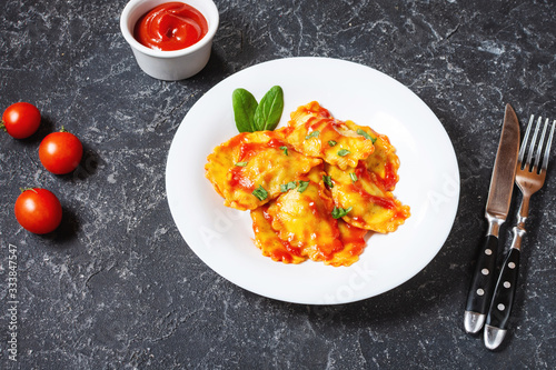 Ravioli with tomato sauce and basil on a dark stone background. Delicious pasta