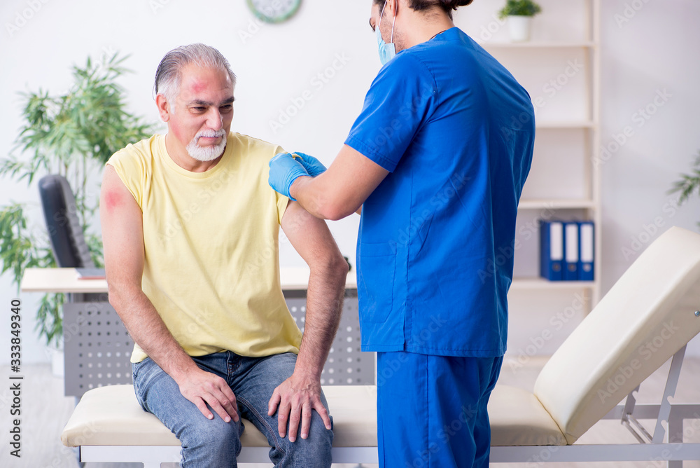 Fototapeta premium Injured old man visiting young male doctor traumatologist