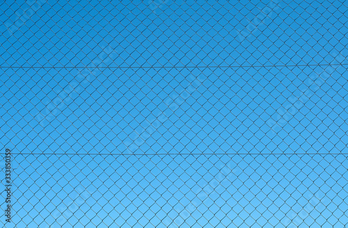 blue sky seen through a chain link fence