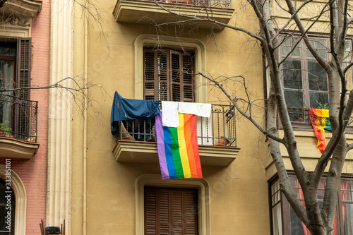 Gay rainbow flag hanging on a balcony with laundry in Barcelona. Human rights concept. 