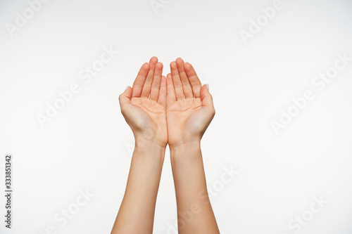 Studio shot of attractive fair-skinned hands of young female forming together, going to pick up water in folded palms. Body language and gesturing