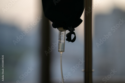 close up to the medical tool, saline drip in the dark silhouette theme on the evening window light.