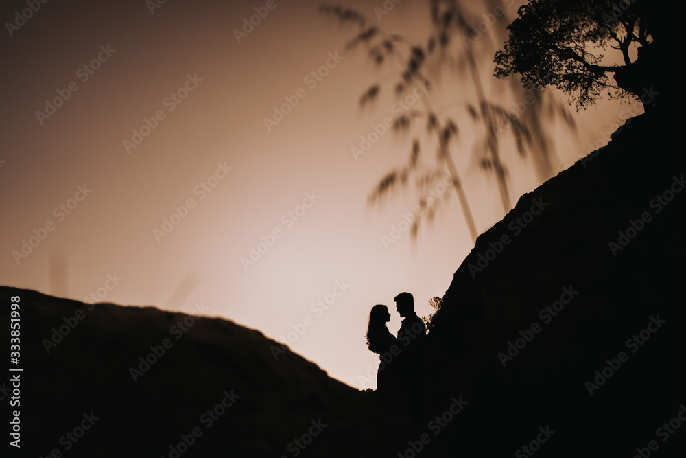 Couple silhouette enjoying romantic colorful sunset in love