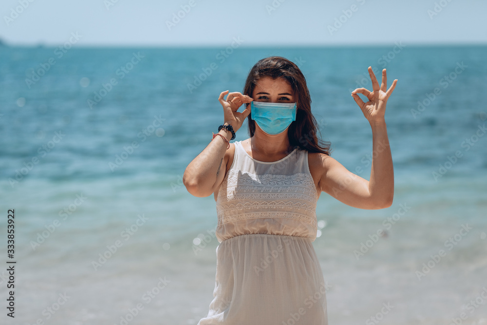 Pretty fit lady travel wearing face protection and showing okay in prevention for coronavirus because of the Outbreak of coronovirus infection COVID-19 and for personal hygiene.