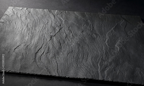 black matte slate natural stone plate with textured surface on gray background