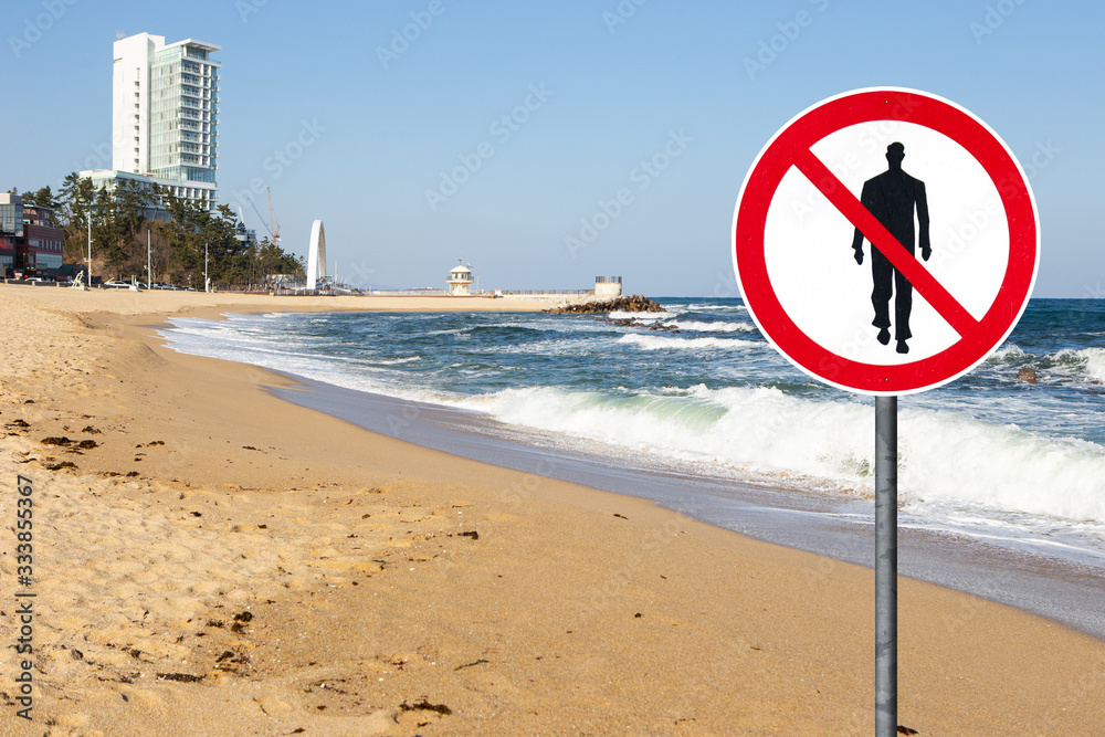 Beach with prohibition sign of people walking. Quarantine self-isolation