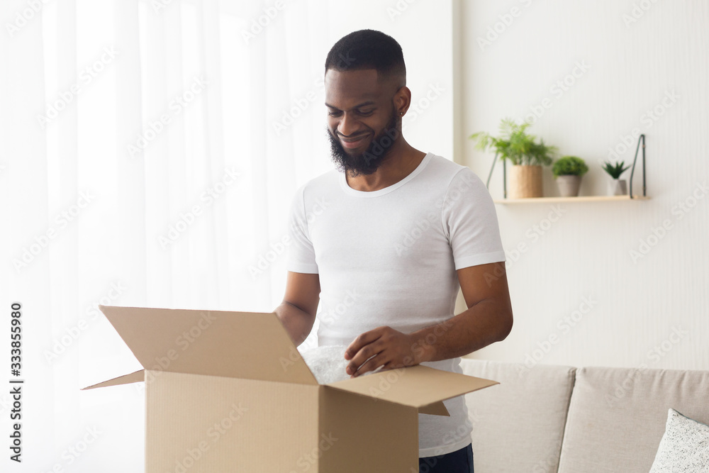 African american guy looks at purchase in box and smiles
