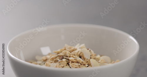 closeup granola with almond flakes in white bowl © GCapture