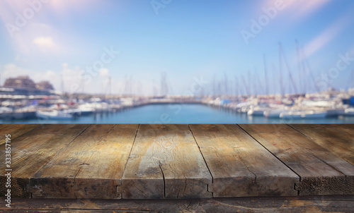 background of wood deck in front of blurred marina beach and sea with boates, yacht. ready for product display © tomertu