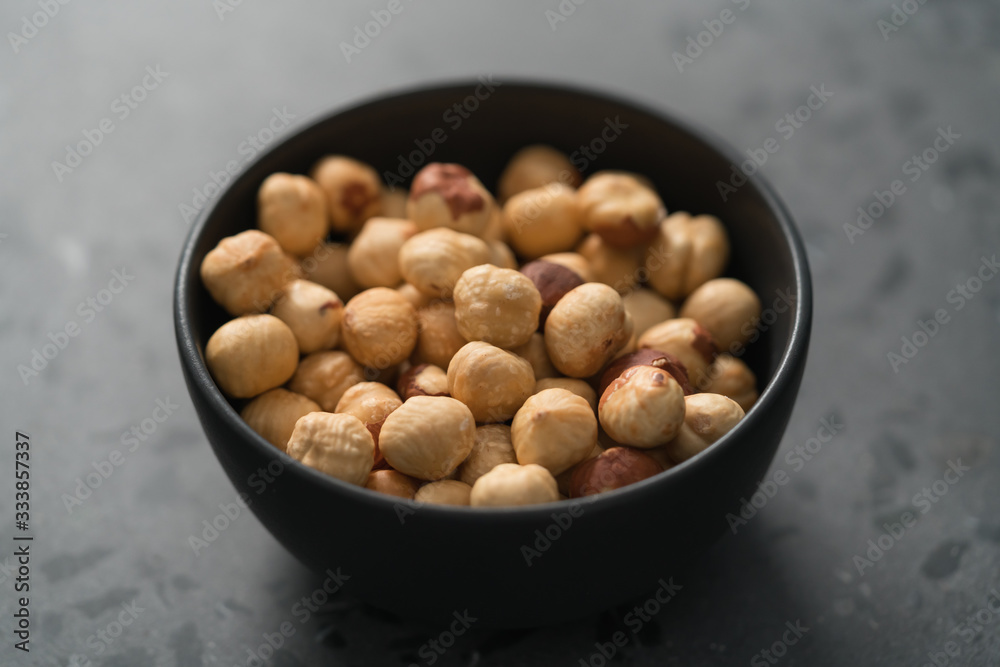 roasted hazelnuts in black bowl on terrazzo countertop roasted hazelnuts in black bowl on terrazzo countertop
