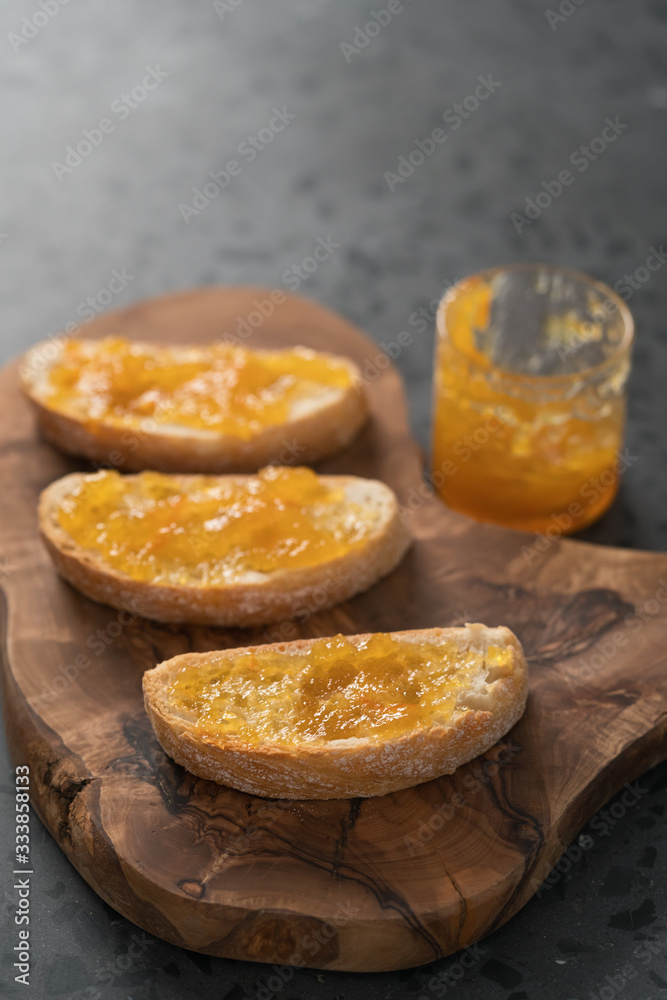 Ciabatta slices with orange marmalade on olive board
