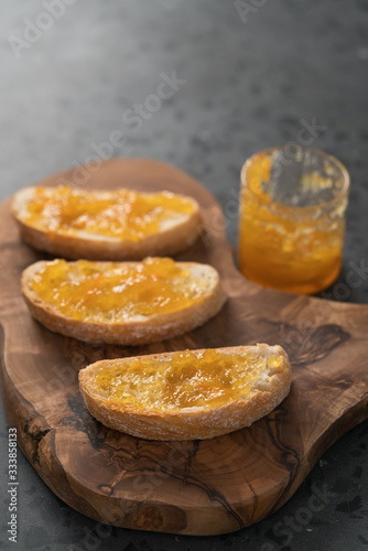 Ciabatta slices with orange marmalade on olive board