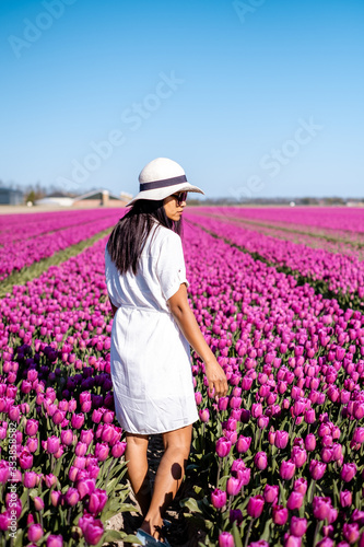 Dutch tulip field, woman with dress and summer hat in tulips field Netherlands,happy young woman in pink flower field