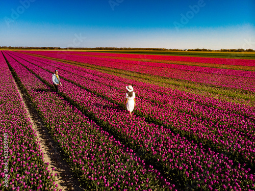 Canvas Print Dutch tulip field, couple in flower field, woman with dress and summer hat in tu