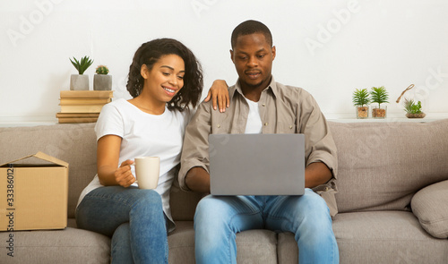 Woman with cup and man with laptop sit on couch