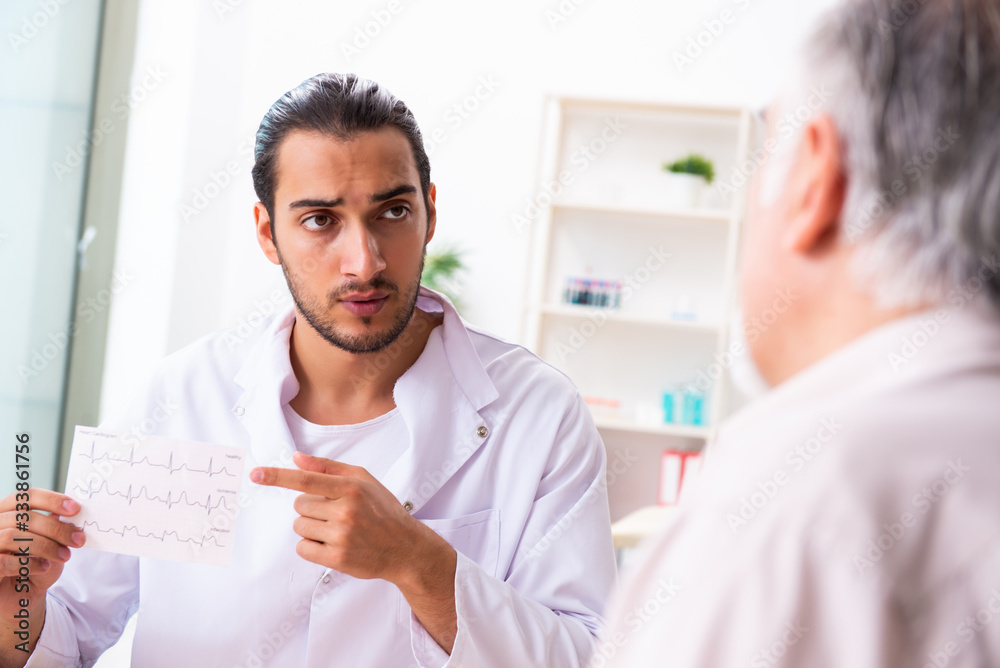 Obraz premium Old man visiting young male doctor cardiologist