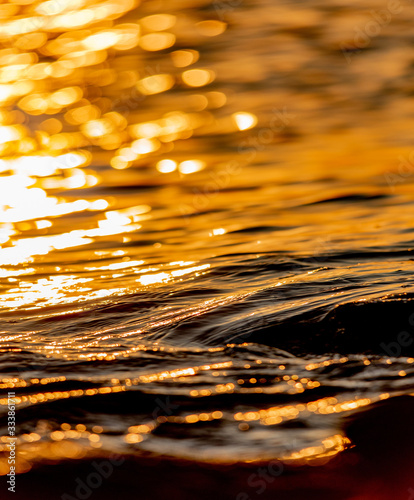 Close-up of sea waves and water movement on the surface of the sea in the golden sunlight. Light reflections on the water.