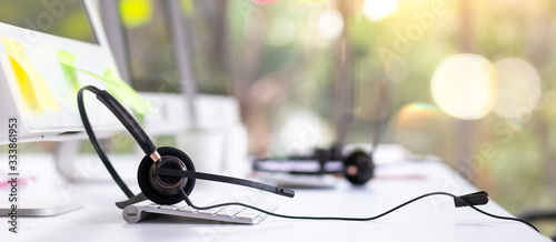  VOIP headset on desk with computer desktop at customer service and marketing support workplace. Office supplies of customer service. Communication support, call center and helpline concept. photo