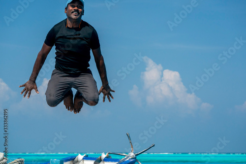 maldivian man jumping in water and diving from boat